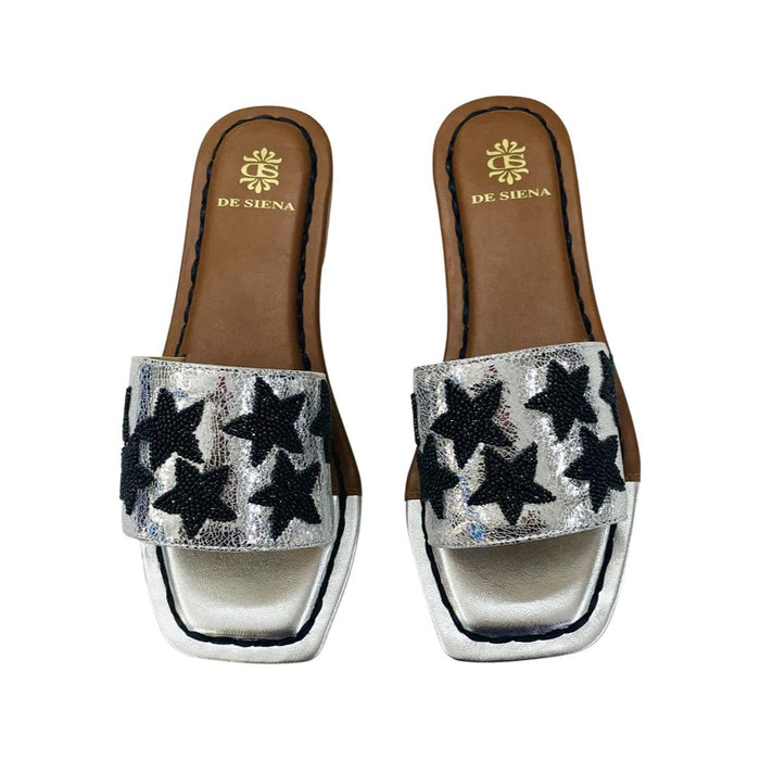 The DE SIENA DA SIENA - BEADED STARS SLIDES are brown and gold metallic open-toe leather slides with a wide strap featuring black beaded star designs and a gold insole outlined in brown with "DE SIENA" branding near the heel.
