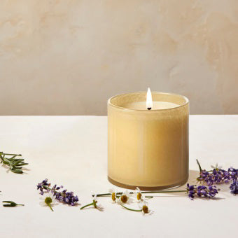 The LAFCO - BEDROOM CHAMOMILE LAVENDER 6.5OZ candle features a soothing blend of lavender and chamomile in a cream-colored wax, set in a simple clear glass container, perfect for relaxing bedroom ambiance.