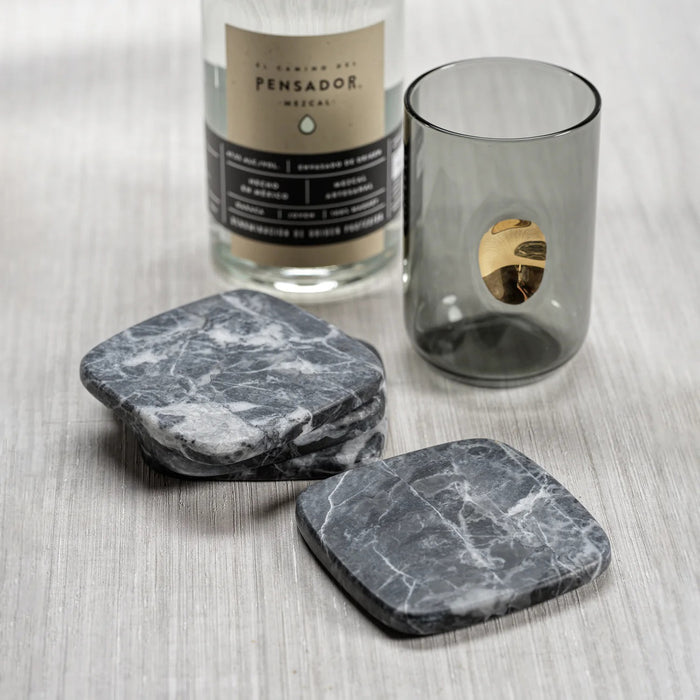 The ZODAX NERO MARQUINE Matte Marble Coasters - Set of 4 features square, dark gray coasters with white veining, elegantly stacked with one shown separately, all displayed on a white background.