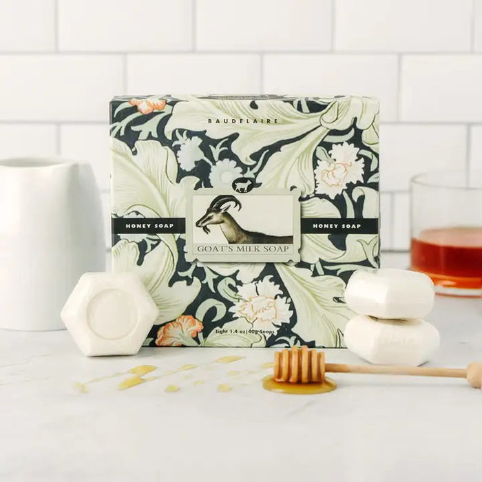 A beautifully designed BAUDELAIRE - GOATS MILK HONEY SOAP 1.4oz Gift Box features eight hexagonal white soaps arranged in an open grid, topped with a floral-patterned lid. These moisturizing BAUDELAIRE soaps are ideal for sensitive skin, providing gentle care with every use.