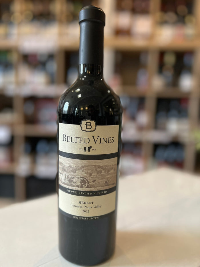 A dark glass bottle labeled "BELTED VINES MERLOT 2022" by WINE: 3 KEYS features a vineyard illustration and notes it is a classic California Merlot, estate grown from Stewart Ranch & Vineyard and barrel aged.