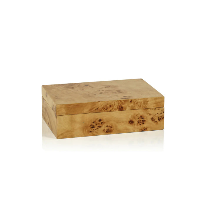 A faceted glass with a brown and cream pattern rests on the ZODAX BURL WOOD DESIGN BOX - SMALL, stacked atop another decorative box, all arranged on a coffee table book titled "Italian Chic.