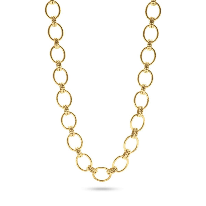 A person in a white blouse displays the CAPUCINE DE WULF - CLEOPATRA GRANDE LINK NECKLACE, made of 18K gold with circular links. Their hands feature gold rings, emphasizing the handmade jewelry's elegance.