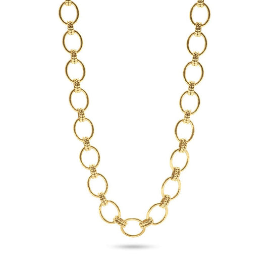 A person in a white blouse displays the CAPUCINE DE WULF - CLEOPATRA GRANDE LINK NECKLACE, made of 18K gold with circular links. Their hands feature gold rings, emphasizing the handmade jewelry's elegance.