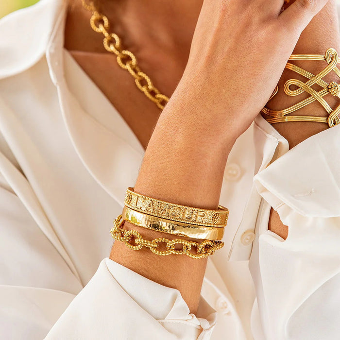 The CAPUCINE DE WULF - CLEOPATRA OVAL HINGED BANGLE SMALL/MEDIUM is a polished, hammered gold bracelet, expertly handcrafted by CAPUCINE DE WULF and displayed against a plain white background.