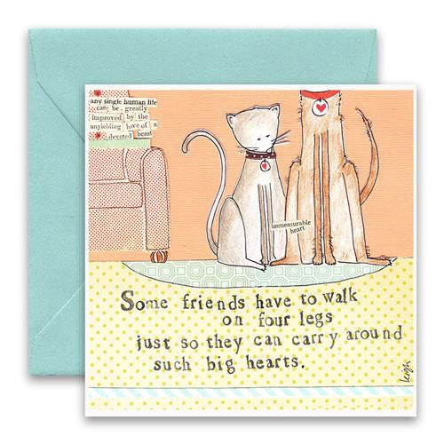 The CURLY GIRL DESIGNS - FOUR LEGS GREETING CARD by CURLY GIRL DESIGN, INC features a cat and dog in front of a sofa with the text: "Some friends have to walk on four legs just so they can carry around such big hearts." Includes light blue envelope.