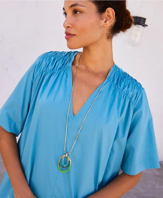 The MOMONI DIP DYED NECKLACE showcases three interlocking oval pendants in gold, white, and coral hues, presented on a plain white background.
