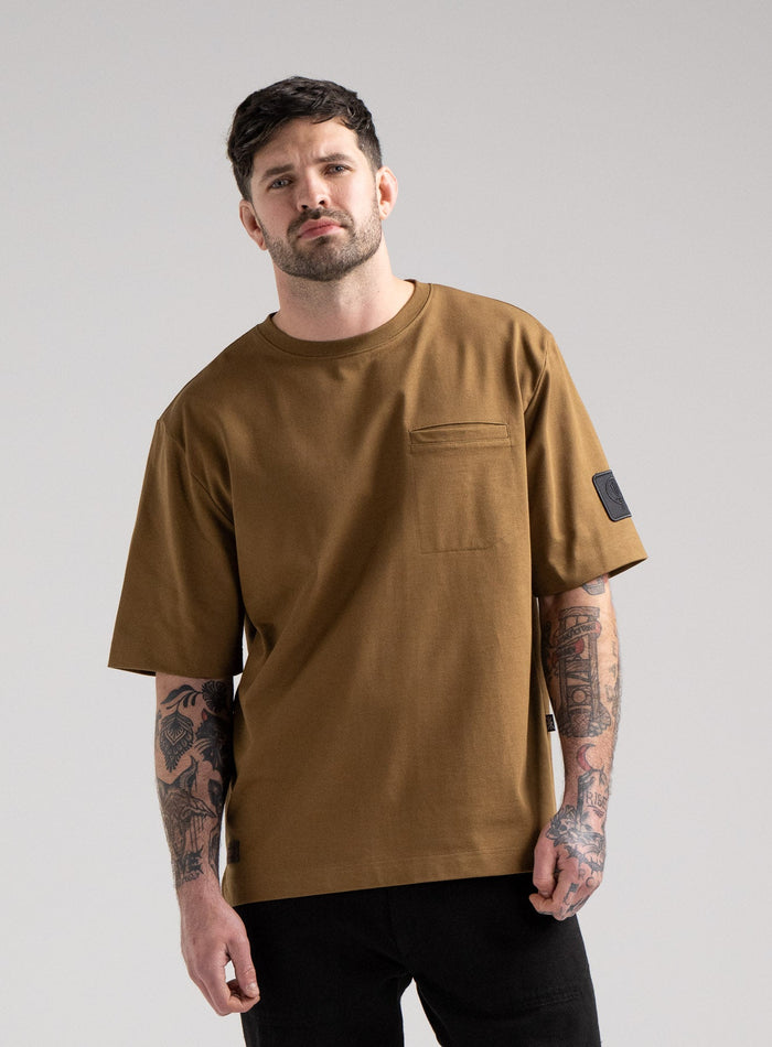 Bernie Is 6ft And Wears Size: M | Hem Studio Image Of Model Wearing Dissident Heavy T-Shirt In Coyote Brown (SS Model)