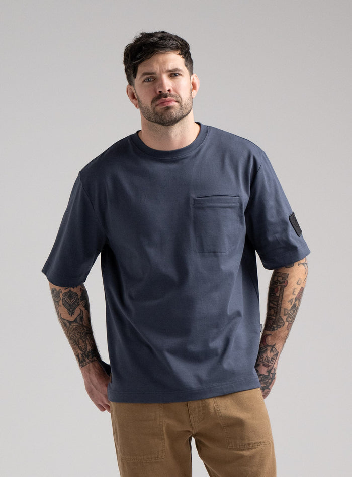 Bernie Is 6ft And Wears Size: M | Hem Studio Image Of Model Wearing Dissident Heavy T-Shirt In Storm Blue (SS Model)