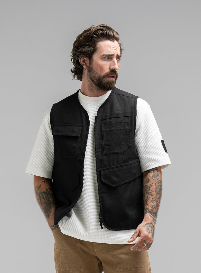 Max Is 5ft 8" And Wears Size: M | Hem Studio Image Of Model Wearing Dissident Utility Vest In Obsidian Black (SS Model)