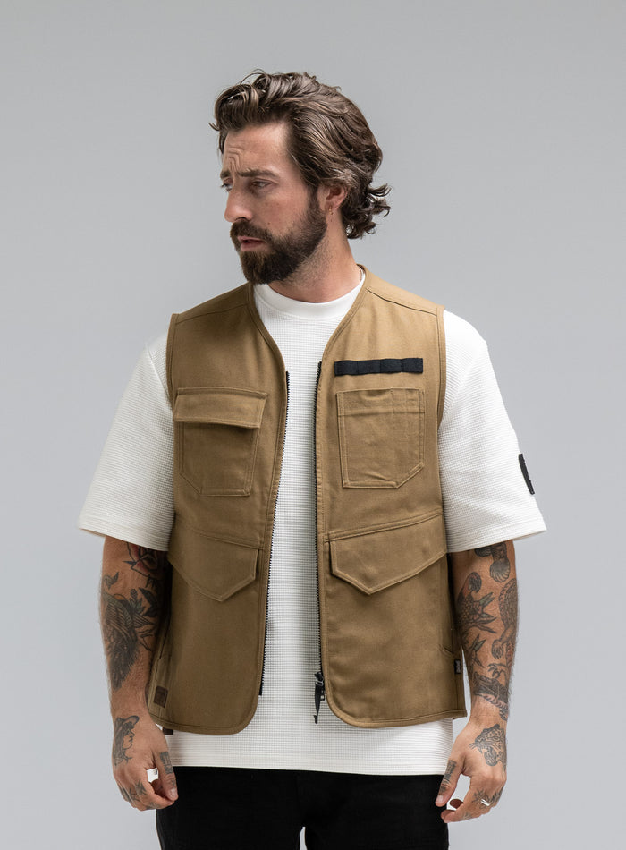Max Is 5ft 8" And Wears Size: M | Hem Studio Image Of Model Wearing Dissident Utility Vest In Coyote Brown (SS Model)