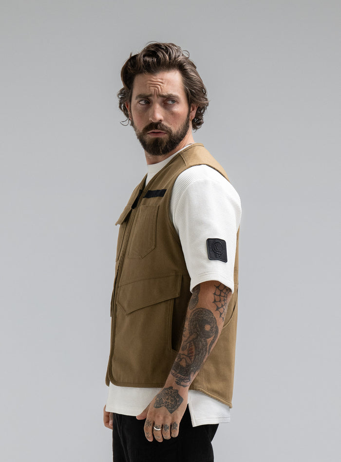 Max Is 5ft 8" And Wears Size: M | Hem Studio Image Of Model Wearing Dissident Utility Vest In Coyote Brown (SS Model)