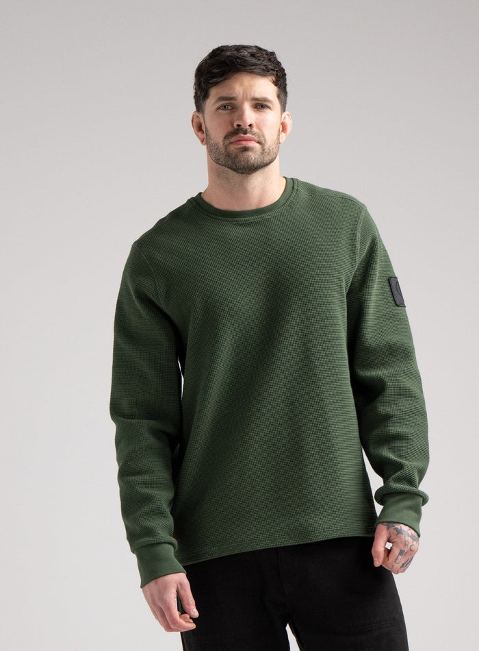 Bernie Is 6ft And Wears Size: M | Hem Studio Image Of Model Wearing Dissident Waffle Long Sleeve T-Shirt In Forest Green (SS Model)