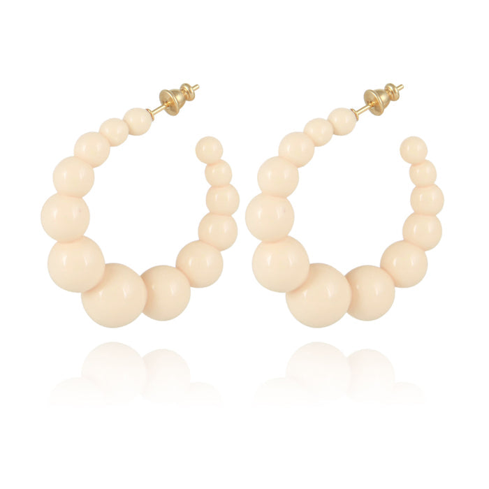 The GAS BIJOUX - CREOLE ANDY EARRINGS are a pair of hoop earrings designed with graduated cream-colored beads that mimic delicate acetate pearls, arranged from smaller at the top to larger toward the bottom. These sophisticated earrings come with a gold-tone post and backing, blending classic charm with a modern flair.