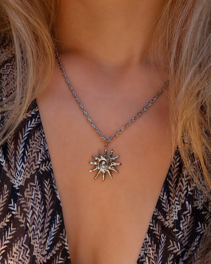 Woman wearing a silver spiral sun pendant necklace made in Greece, Greek jewelry