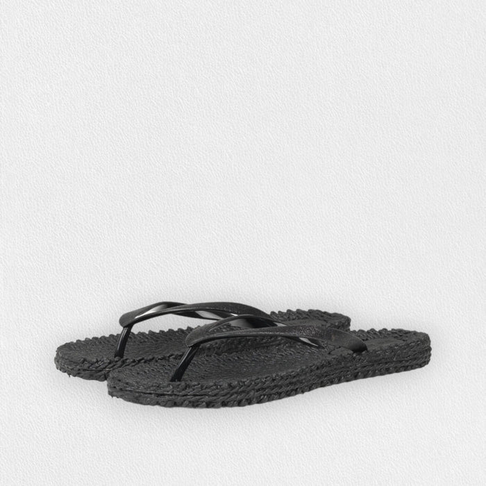 The ILSE JACOBSEN - CHEERFUL FLIP FLOP IN BLACK by LINES OF DENMARK features black braided-texture soles and simple black straps, displayed on a light textured background.