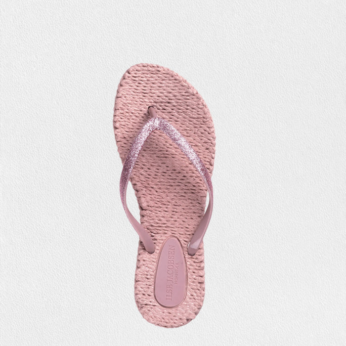 The ILSE JACOBSEN CHEERFUL FLIP FLOPS IN MISTY ROSE by LINES OF DENMARK feature slim plastic straps and braided straw-textured soles, showcased on a light, textured surface.