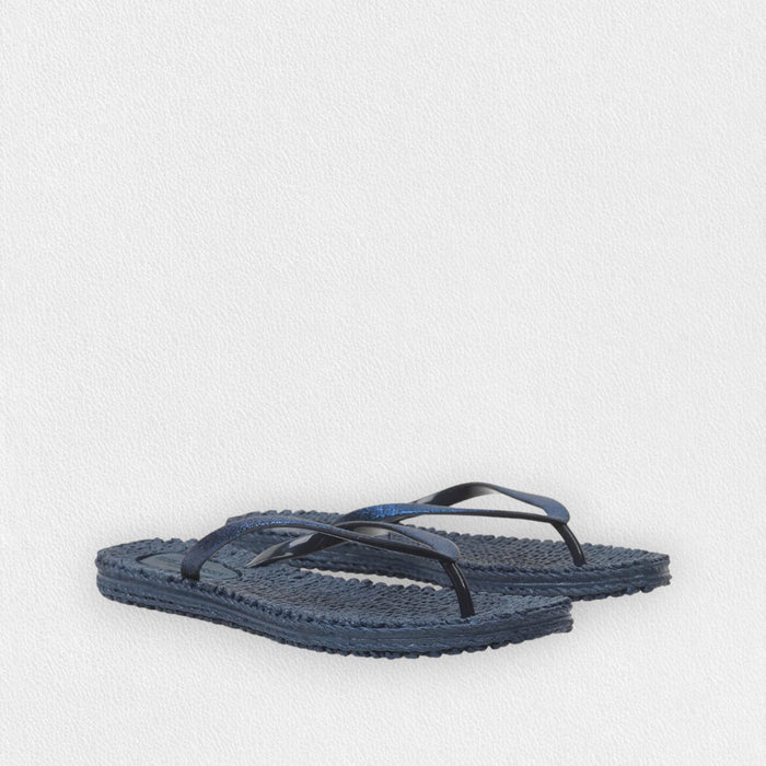 The ILSE JACOBSON CHEERFUL FLIP FLOPS IN INDIGO by LINES OF DENMARK feature lightweight design, textured soles, and dark blue straps, displayed on a light textured background.