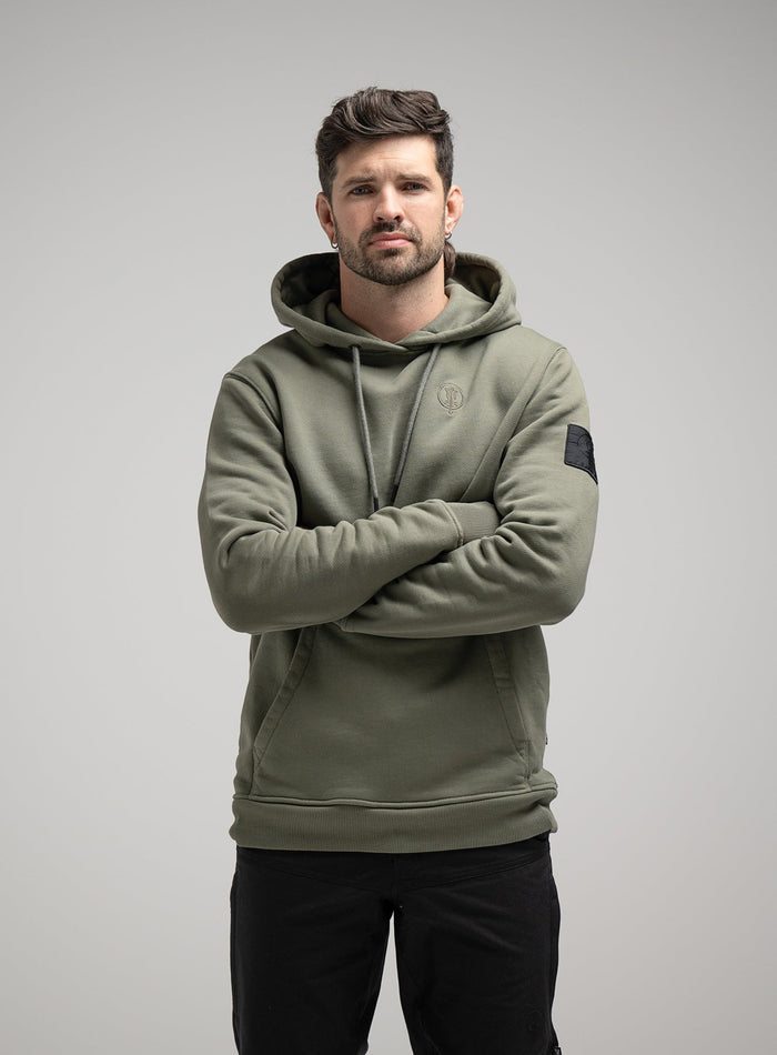 Bernie Is 6ft And Wears Size: M | Hem Studio Image Of Model Wearing Insignia Hoody Washed In Khaki (SS Model)