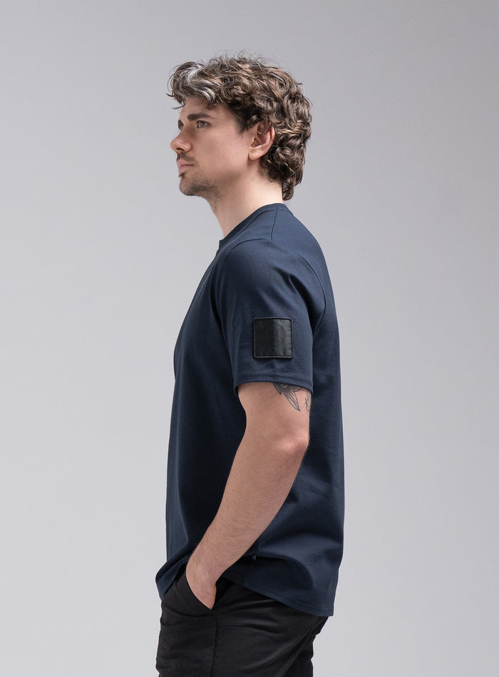 Jack Is 6ft 3" And Wears Size: L | Hem Studio Image Of Model Wearing Insignia Short Sleeve T-Shirt In Dark Sapphire (SS Model)