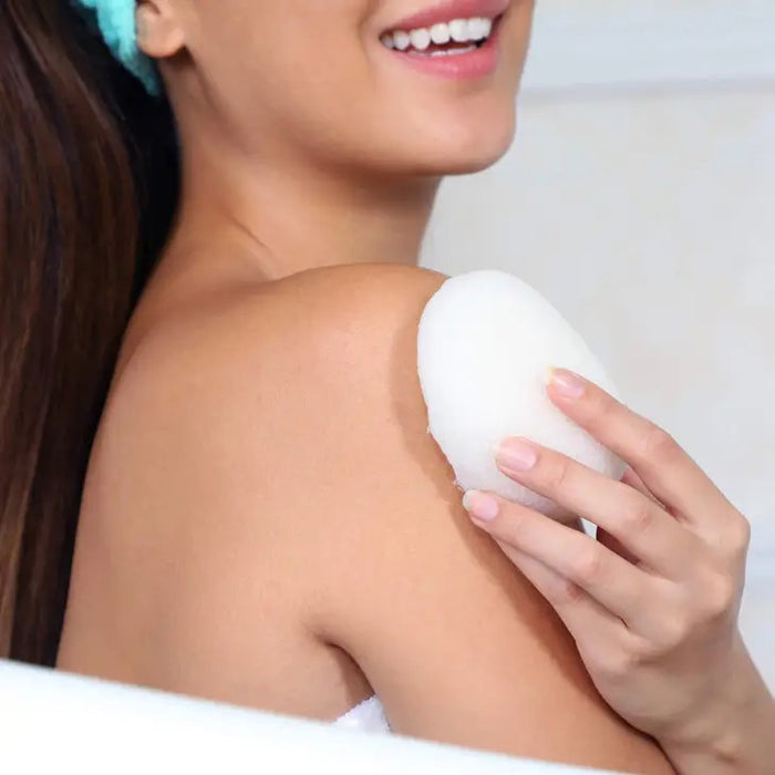 A package labeled "DAILY CONCEPTS KONJAC SPONGE - PURE" sits beside a white oval-shaped sponge. Inspired by Japanese rituals, this biodegradable, vegan konjac root sponge gently cleanses and balances skin pH.
