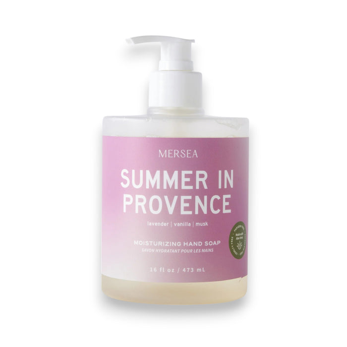 A clear pump bottle of MERSEA - SUMMER IN PROVENCE HAND SOAP 16OZ sits on a pink and white gradient background, offering soothing lavender and sweet vanilla scents.