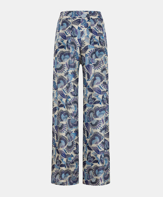 The MOMONI - ASPEN PANT features a luxurious haboutai silk fabric with a geometric pattern of squares and rectangles, adorned with vibrant floral motifs and architectural designs in colors like yellow, green, and blue.