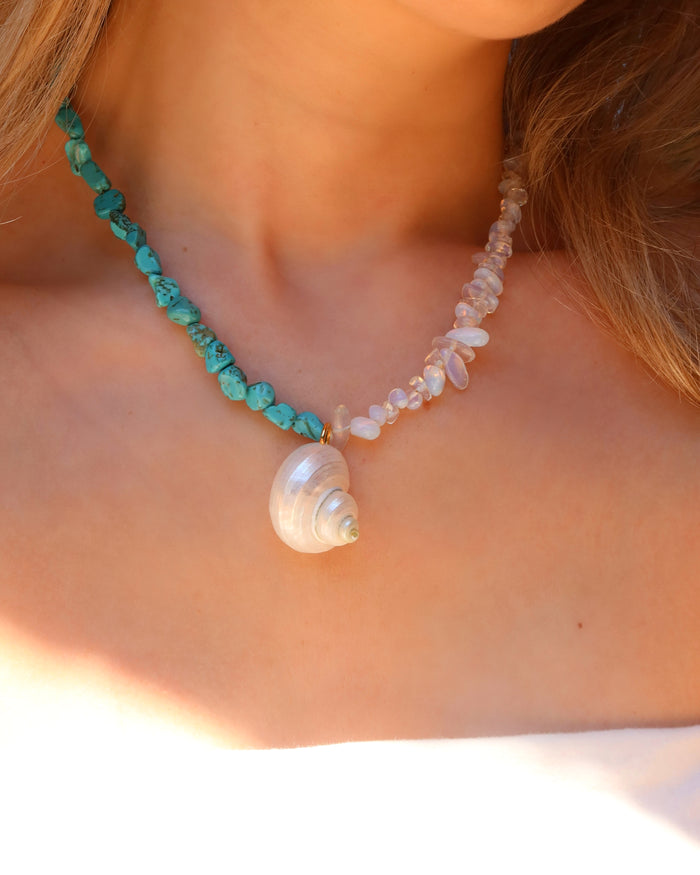 Woman wearing a turquoise and moonstone beaded necklace with a shell pendant made in Greece, summer beach jewelry