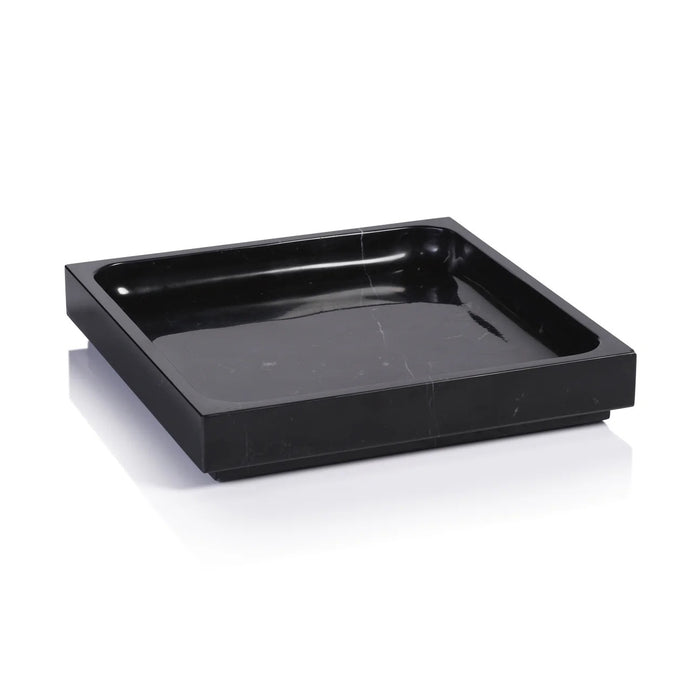 A black bottle of tequila sits on a ZODAX NERO MARQUINA NATURAL MARBLE TRAY - LARGE, accompanied by a black goblet and bowl of chocolate treats, all arranged on a light surface with a dark backdrop.