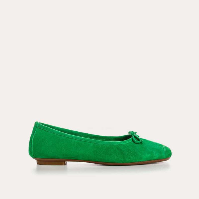 Top view of the REQINS - HARMONY suede ballerina flat in Gazon Green, featuring a small bow on the toe, photographed on a plain light background.