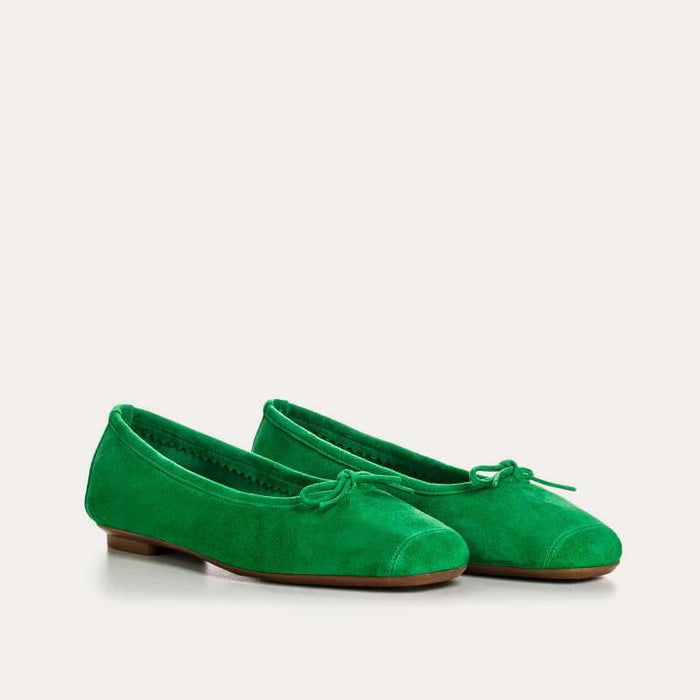 Top view of the REQINS - HARMONY suede ballerina flat in Gazon Green, featuring a small bow on the toe, photographed on a plain light background.