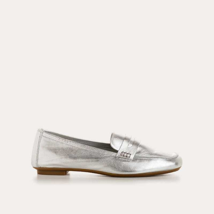 The REQINS HEMA Metallic Loafer in Silver is photographed from above on a light background, revealing its shimmering leather and the brand’s name visible on the dark insole.