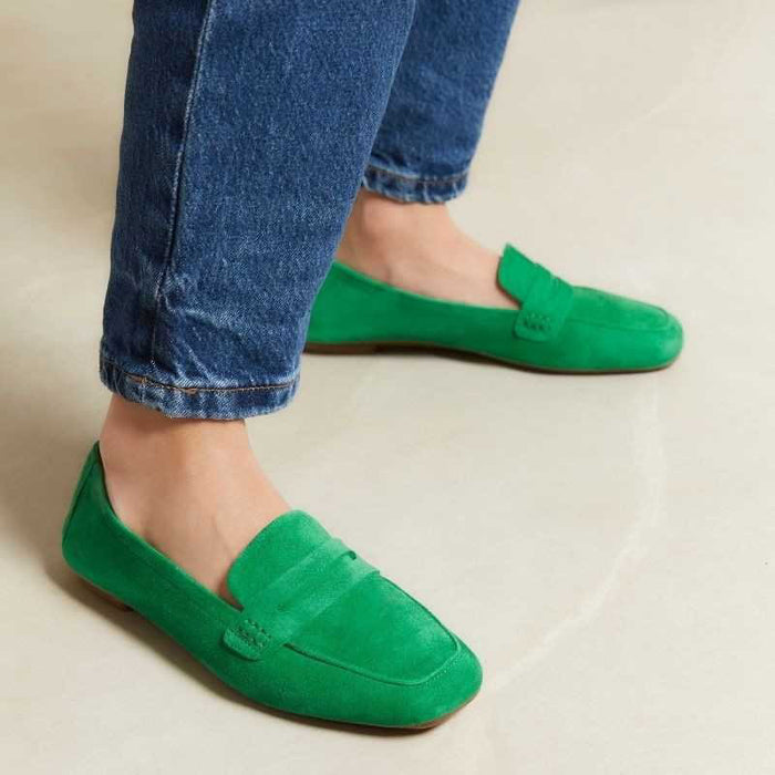 A person stands on a light floor wearing blue jeans and REQINS - HEMA SUEDE LOAFER IN GAZON GREEN by REQINS, featuring a leather insole.