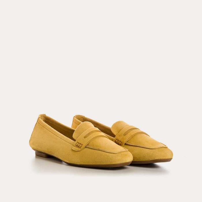 The REQINS - HEMA Suede Loafer in Ochre, expertly crafted by REQINS, features a low heel and a decorative front strap, shown against a plain light background.