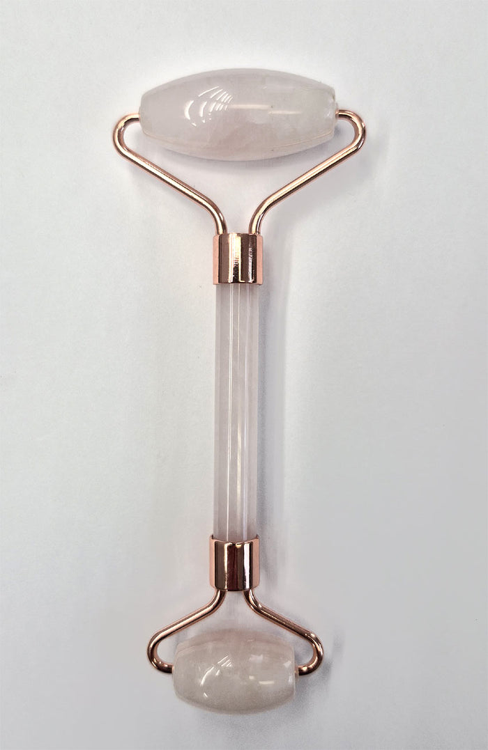 Jade facial roller with rose gold accents on a light gray background