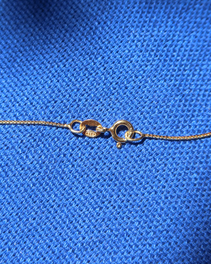 Spring ring clasp and gold chain necklace made in Greece on blue background