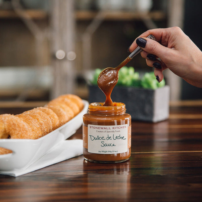 A glass jar of STONEWALL KITCHEN- DULCE DE LECHE SAUCE with a green lid, labeled gluten free, net weight 369g (13 oz.)—perfect for adding a Caribbean twist to your favorite desserts.