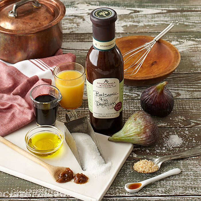 A bottle of STONEWALL KITCHEN-BALSAMIC FIG DRESSING by STONEWALL KITCHEN, featuring a brown liquid and a green and cream label with handwritten-style text—ideal as a flavorful salad dressing.