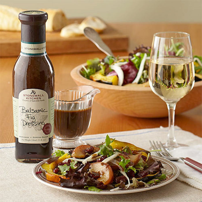 A bottle of STONEWALL KITCHEN-BALSAMIC FIG DRESSING by STONEWALL KITCHEN, featuring a brown liquid and a green and cream label with handwritten-style text—ideal as a flavorful salad dressing.