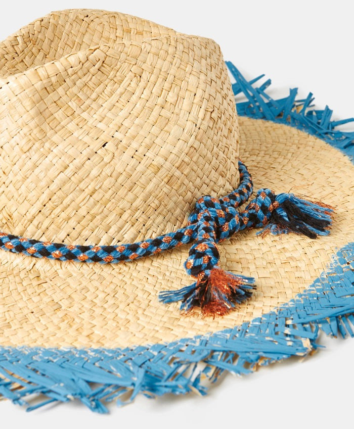 The MOMONI TALLULAH RAFIA SUMMER HAT, crafted in Italy from natural raffia, features a wide fringed brim with a frayed blue edge and a blue braided crown band, displayed on a plain light background.