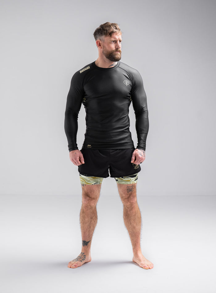 Staz Is 5ft 8" And Wears Size: S | Hem Studio Image Of Model Wearing Thrudark X Scramble Long Sleeve Rash Guard In Obsidian Black (SS Model)