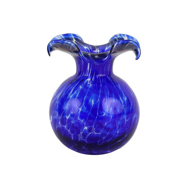 The VIETRI Hibiscus Bud Vase in Cobalt Tortoiseshell is a round, cobalt blue glass vase with a flared, wavy rim and swirling white patterns that evoke the artistic flair of Tuscan artisans.